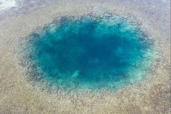 Blue holes are found amid a shallow reef flat on the island of Sebayor in Komodo National Park, Indonesia. These blue holes formed as sink holes