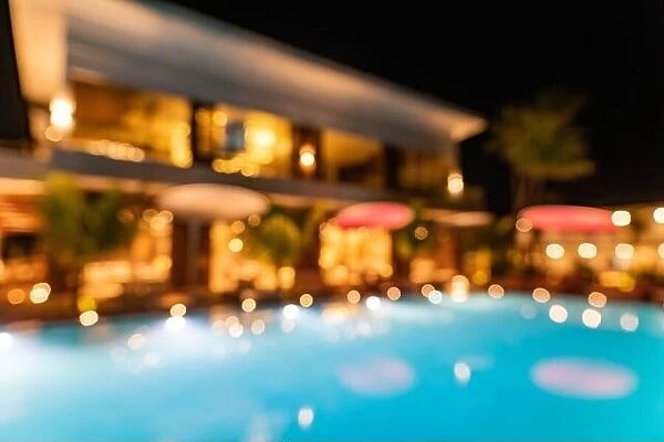 Blur lights reflection in infinity swimming luxury pool party water at night background. Resort hotel abstract bokeh background summer travel vacation