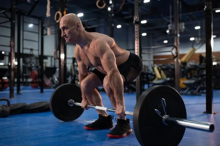 Framed Print : Full body powerful elderly man lifting barbell from floor while exercising during weightlifting training in gym