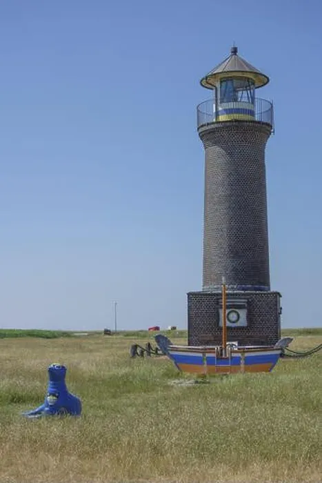 Framed Print : Brick lighthouse next to boat and blue sculpture in a meadow under blue sky, juist, north sea, germany Framed Print : Brick lighthouse next to boat and blue sculpture in a meadow under blue sky, juist, north sea, germany