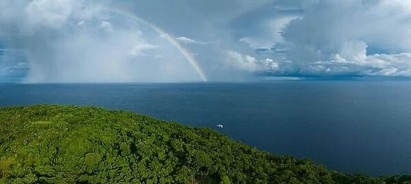 A bright rainbow appears behind a remote tropical island in the Solomon Islands. This beautiful country is home to spectacular marine biodiversity