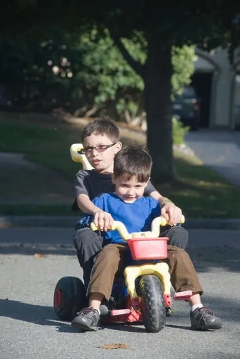 Framed Print : Two brothers, age seven and four ride a big wheel three wheeler in their driveway Framed Print : Two brothers, age seven and four ride a big wheel three wheeler in their driveway