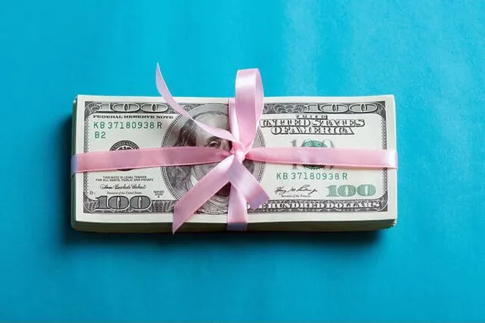Framed Print : a bundle of dollars tied with a pink ribbon on a blue background Framed Print : a bundle of dollars tied with a pink ribbon on a blue background