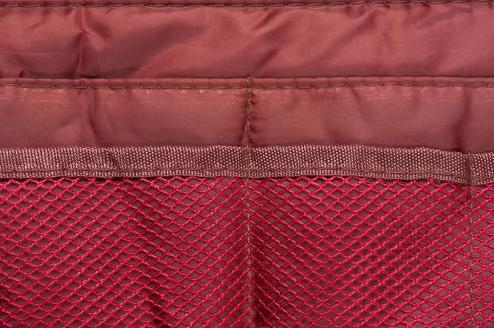 Framed Print : Burgundy travel bag organizer with pockets from mesh fabric, close-up Framed Print : Burgundy travel bag organizer with pockets from mesh fabric, close-up