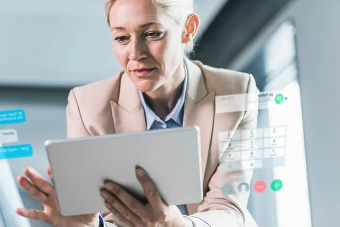 Framed Print : Businesswoman sitting in office, using digital tablet Framed Print : Businesswoman sitting in office, using digital tablet