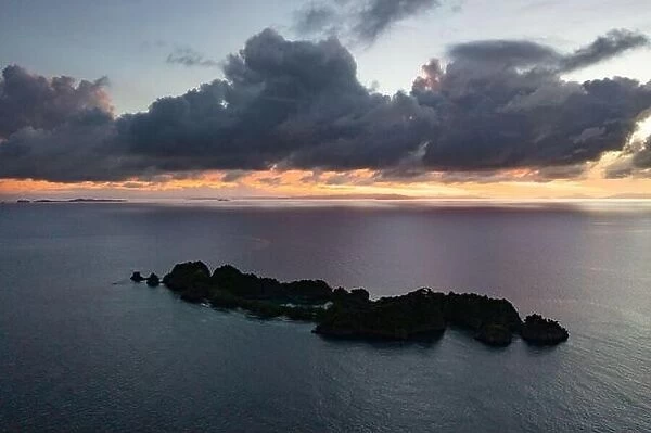 A calm dawn silhouettes beautiful limestone islands in Raja Ampat, Indonesia. This remote, tropical area is known as the heart of the Coral Triangle