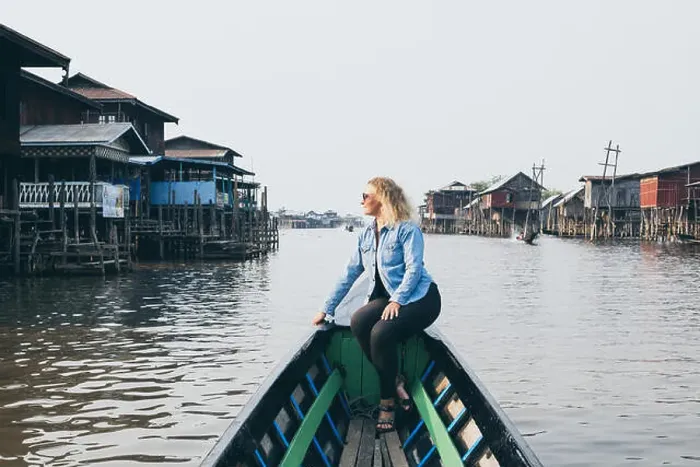 Framed Print : Caucasian blonde woman in denim shirt having a boat ride along floating houses on Inle lake, Myanmar