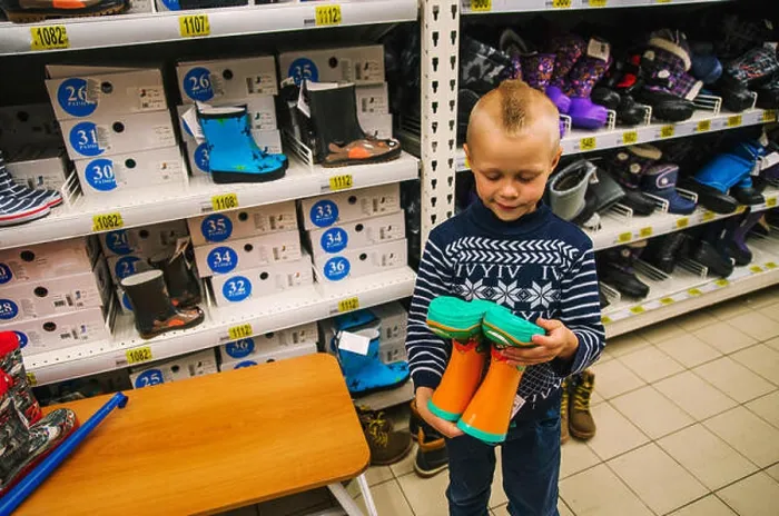 Framed Print : Caucasian boy admiring boots in store Framed Print : Caucasian boy admiring boots in store