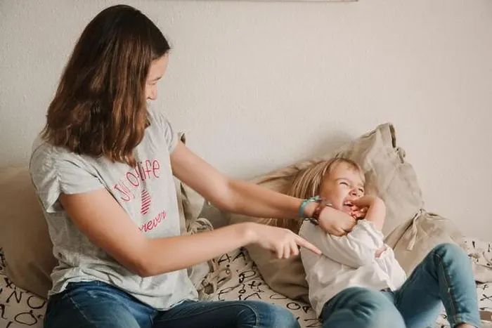Framed Print : Cheerful teen girl sitting on bed and tickling laughing sister while playing together at home during weekend Framed Print : Cheerful teen girl sitting on bed and tickling laughing sister while playing together at home during weekend
