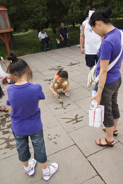 Framed Print : chinese girls practicing calligraphy with water on the pavement in front of the temple of heaven, beijing, china