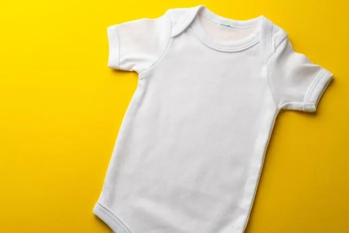 Framed Print : Close up of baby white t shirt with copy space on yellow background Framed Print : Close up of baby white t shirt with copy space on yellow background