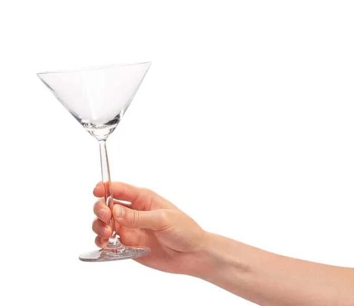 Framed Print : Close up of female hand holding empty clean transparent martini glass against white background Framed Print : Close up of female hand holding empty clean transparent martini glass against white background