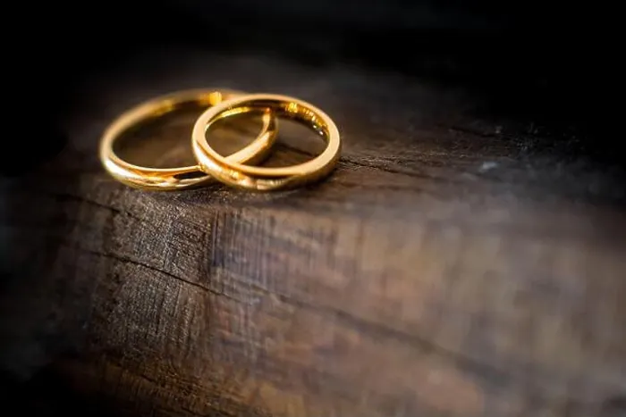Framed Print : Close up of two golden wedding rings lying on the edge of an ancient and weathered wooden table Framed Print : Close up of two golden wedding rings lying on the edge of an ancient and weathered wooden table