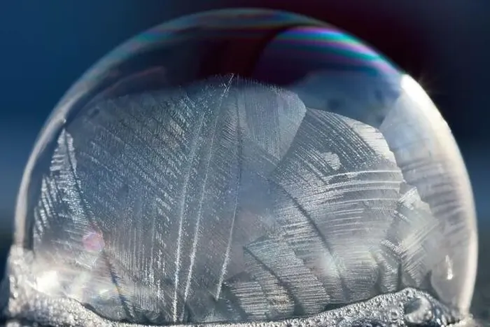 Framed Print : Close-up macro of a frozen soap bubble with abstract pattern in winter sunlight, isolated on blue Framed Print : Close-up macro of a frozen soap bubble with abstract pattern in winter sunlight, isolated on blue