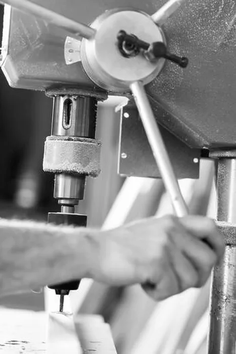 Framed Print : Close up view of a carpenter's hands operating a bench drill press on a piece of wood in a workshop. - black n white - Framed Print : Close up view of a carpenter's hands operating a bench drill press on a piece of wood in a workshop. - black n white -