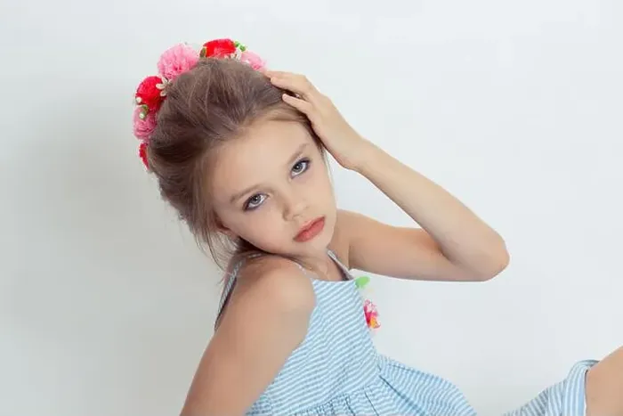 Framed Print : Closeup beautiful little girl wreath of flowers on head posing in studio hand on head isolated white grey background Framed Print : Closeup beautiful little girl wreath of flowers on head posing in studio hand on head isolated white grey background