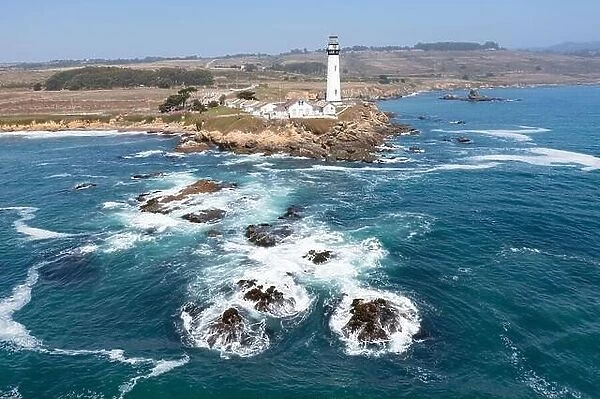 Cold Pacific Ocean waves crash against the rugged California coastline where a scenic lighthouse stands north of Santa Cruz