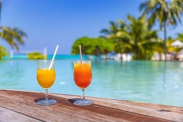 Colorful cocktails served on luxury tropical resort hotel in Maldives. Poolside with blurred palm trees beds umbrellas. Bright sunny pool