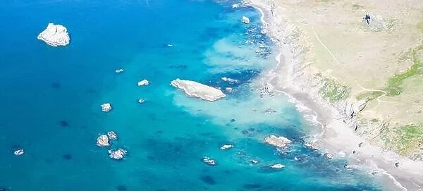 The colorful and almost peaceful Pacific Ocean washes against the rocky Northern California coastline on a beautiful day