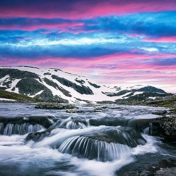 Colorful sunrise on snowy norwegian mountains and clear river near the famous Aurlandsvegen (Bjorgavegen), mountain road, Aurland, Norway