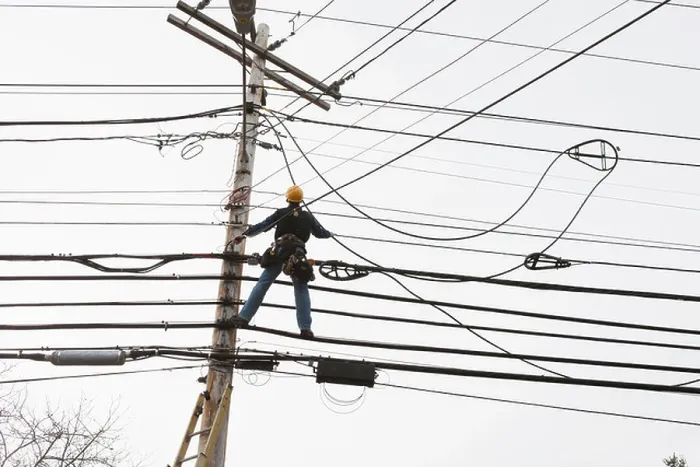 Framed Print : Communications worker on a power pole installing new cable to existing bundles Framed Print : Communications worker on a power pole installing new cable to existing bundles