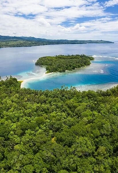 A coral reef surrounds idyllic, tropical islands off the coast of New Britain in Papua New Guinea. This area is part of the Coral Triangle
