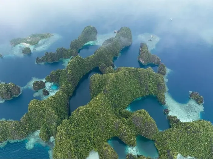 Framed Print : Coral reefs surround the rugged limestone islands that rise from Raja Ampat's seascape. This remote part of Indonesia has high marine biodiversity