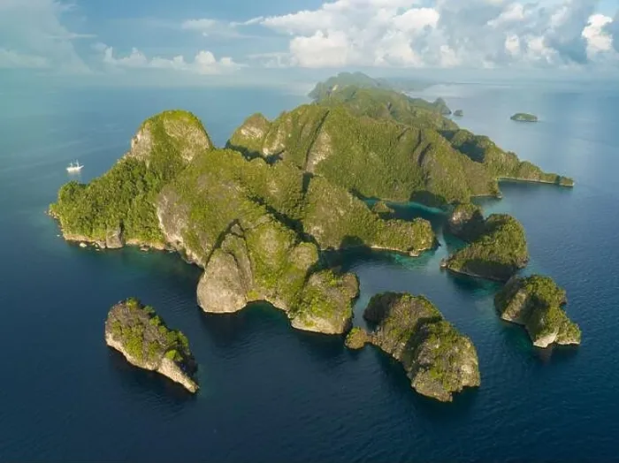 Framed Print : Coral reefs surround the rugged limestone islands that rise from Raja Ampat's seascape. This remote part of Indonesia has high marine biodiversity