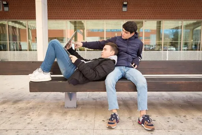 Framed Print : couple two gay university students together on a bench using laptop computer