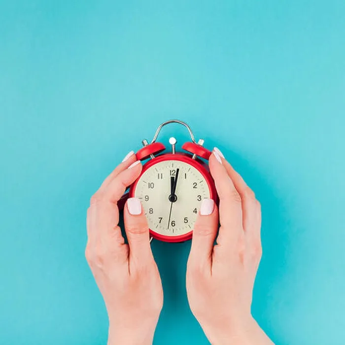 Framed Print : Creative flat lay concept top view of woman hands holding the red vintage alarm clock on square bright blue turquoise
