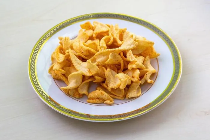 Framed Print : Crispy twist potato chips or aloo chips with tomato and paprika flavor, served on a white plate on a light wooden table