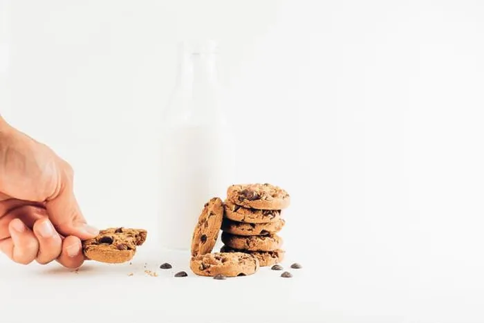 Framed Print : Crop unrecognizable person eating sweet chocolate chips cookies on table with bottle of milk on white background Framed Print : Crop unrecognizable person eating sweet chocolate chips cookies on table with bottle of milk on white background