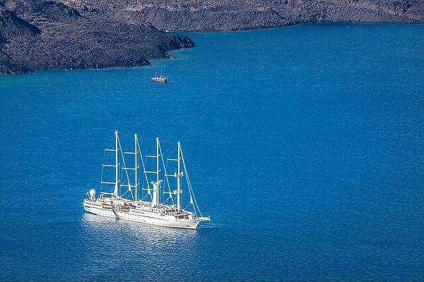 Cruise ship near Santorini, summer travel tourism boats in blue sea bay, cliffs of Santorini volcano island. Famous travel destination