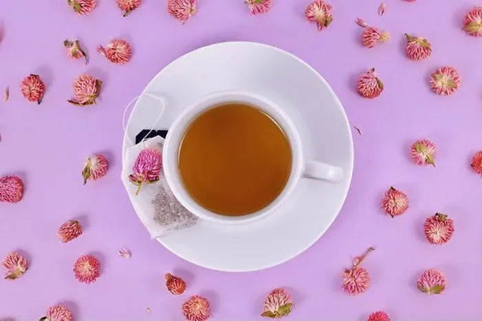 Framed Print : Cup of tea surrounded by dried globe amaranth flowers on violet background Framed Print : Cup of tea surrounded by dried globe amaranth flowers on violet background