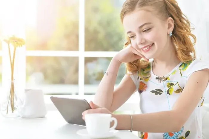 Framed Print : Cute little girl sitting at table and looking at laptop Framed Print : Cute little girl sitting at table and looking at laptop