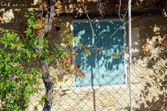 Framed Print : Cyprus, A light beige stone wall with a blue shutter and a white metal fence in front of it Framed Print : Cyprus, A light beige stone wall with a blue shutter and a white metal fence in front of it