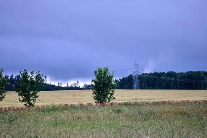Framed Print : Dark clouds loom above golden fields while trees stand peacefully alongside power lines in a remote countryside setting Framed Print : Dark clouds loom above golden fields while trees stand peacefully alongside power lines in a remote countryside setting