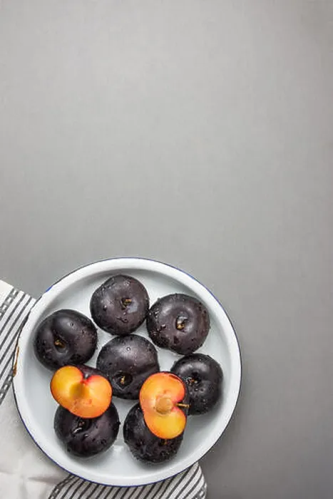 Framed Print : Dark red big plums whole and halved on white vintage enamel plate Framed Print : Dark red big plums whole and halved on white vintage enamel plate