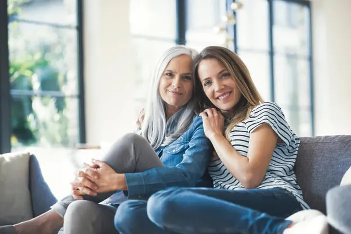 Framed Print : Daughter holding mother in her arms, sitting on couch Framed Print : Daughter holding mother in her arms, sitting on couch