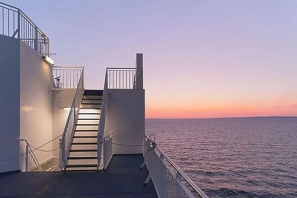 Deck of a cruise ship during sunset. Calm ocean and clear pink sky in evening time. Cruise vacations background. Minimalism in photography