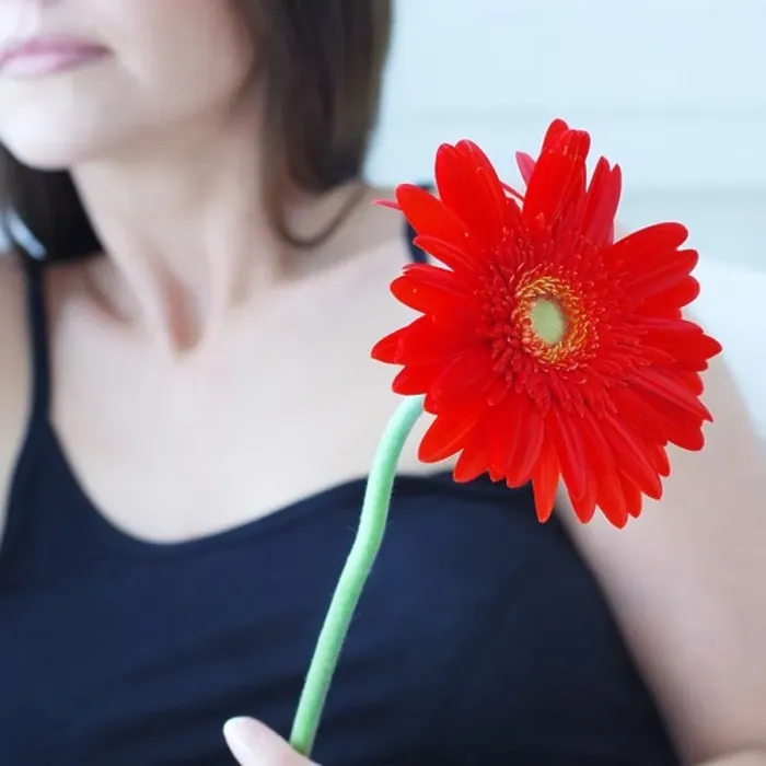Framed Print : Defocused attractive woman holding red flower Framed Print : Defocused attractive woman holding red flower