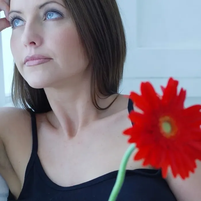 Framed Print : Defocused attractive woman holding a red flower Framed Print : Defocused attractive woman holding a red flower