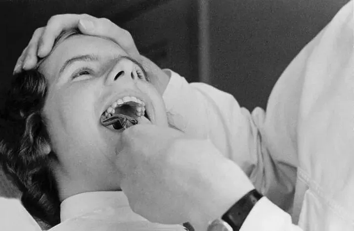 Framed Print : At the dentist in the 1940s. A woman patient is having one of her teeth pulled Framed Print : At the dentist in the 1940s. A woman patient is having one of her teeth pulled