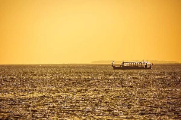 Dhoni Maldivian boats on wonderful golden sunset in Maldives. Traditional wooden boat, sunset sea
