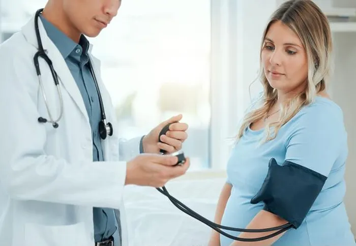 Framed Print : a doctor using a blood pressure gauge during a checkup with his pregnant patient