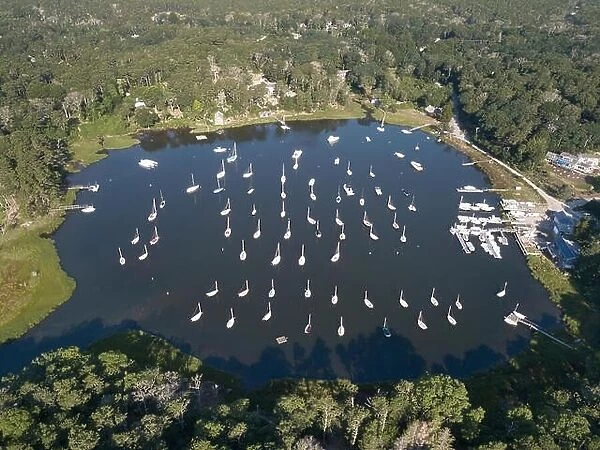 Dozens of sailboats are moored in a calm bay on Cape Cod, Massachusetts. This peninsula is a popular summer vacation destination in New England