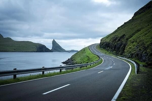 Dramatic evening view of the road and the Drangarnir and Tindholmur rocks in the background on the island of Vagar, Faroe Islands, Denmark