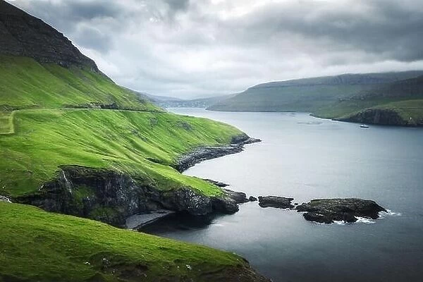 Dramatic view of green hills of Vagar island and Sorvagur town on background. Faroe islands, Denmark. Landscape photography