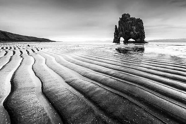 Drammatic landscape with famous Hvitserkur rock and dark wavy sand after the tide. Vatnsnes peninsula, Iceland, Europe. Black and white photo