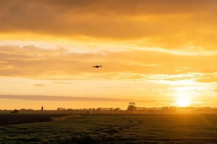 Framed Print : A drone flying over green springtime meadows with a colorful orange sunset sky behind Framed Print : A drone flying over green springtime meadows with a colorful orange sunset sky behind